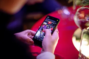 App 1CCC — Rápido, responsivo e otimizado para todos os dispositivos Uma mulher alegre em roupas tradicionais usando seu smartphone durante um momento festivo, mostrando como o app 1CCC se encaixa facilmente no dia a dia.
