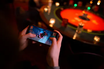 Um jogador usando seu smartphone durante um evento festivo local, representando o cassino totalmente compatível com dispositivos móveis do 1CCC.